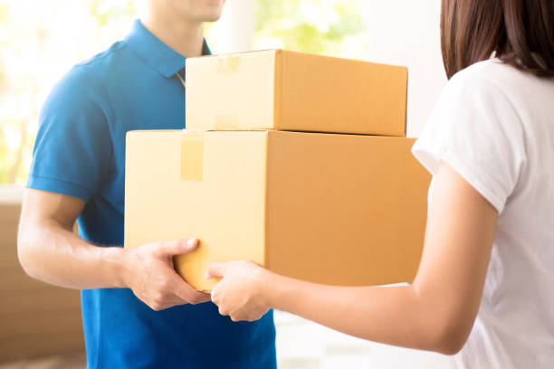 Woman receiving packages from courier Woman receiving packages from a delivery man door to door salesperson photos stock pictures, royalty-free photos & images