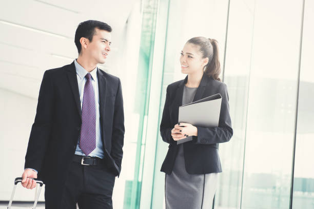 istock Businessman walking and pulling luggage handle while talking with a businesswoman 1092392814