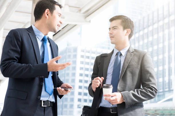 Businessmen discussing while walking to work in the morning Interracial businessmen discussing while walking to work in the morning at outdoor covered walkway office buddies stock pictures, royalty-free photos & images
