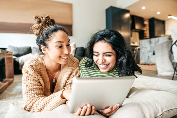 Social media for students and academic success Two female students with digital tablet and cellphone at home friends laughing stock pictures, royalty-free photos & images