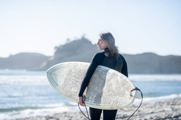 istock A female surfer walking along the beach 1092409178