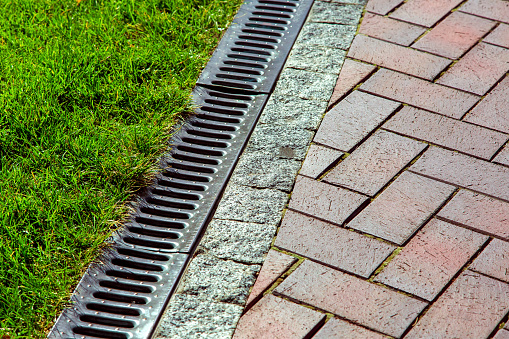 iron drainage net between paving slab and green lawn.