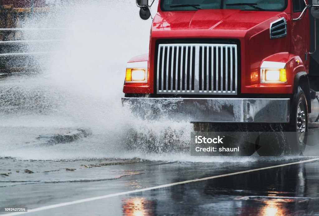 Dump Truck in Flooding A dump truck navigates a flooded portion of highway after heavy rains. Semi-Truck Stock Photo