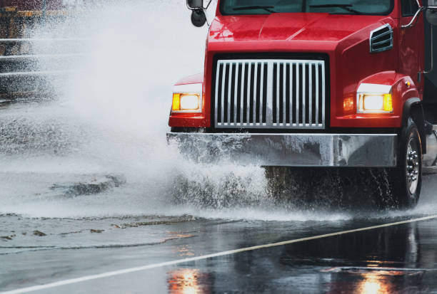 Dump Truck in Flooding A dump truck navigates a flooded portion of highway after heavy rains. truck rain stock pictures, royalty-free photos & images