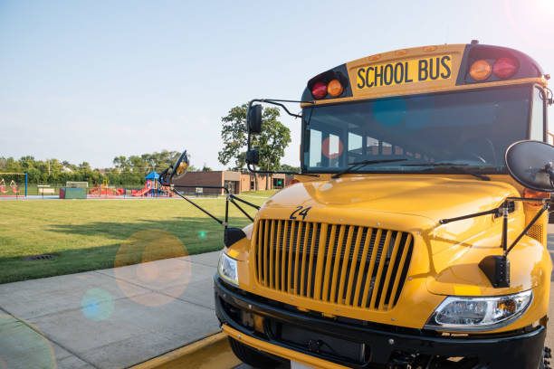 遊び場の隣に駐車した黄色いスクールバス - front view bus photography day ストックフォトと画像