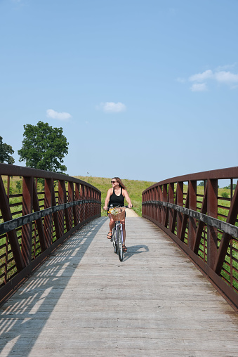 woman smiling and riding bicycle over bridge on bike path