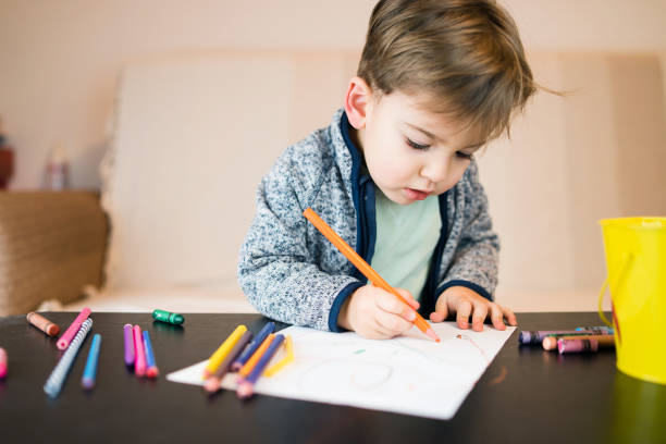 istock Little Boy Drawing On Paper With Crayons 1092438204