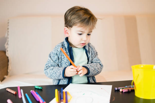 istock Little Boy Drawing On Paper With Crayons 1092438210