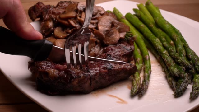 Ribeye Beef steak on a plate with asparagus ready to eat