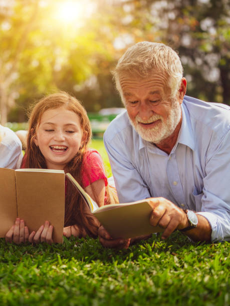 szczęśliwa rodzina wspólnie czyta książki w parku. - grandmother reading child grandson zdjęcia i obrazy z banku zdjęć