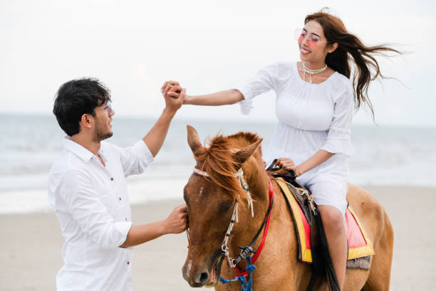istock Young couple goes horse riding on tropical beach. 1092510536