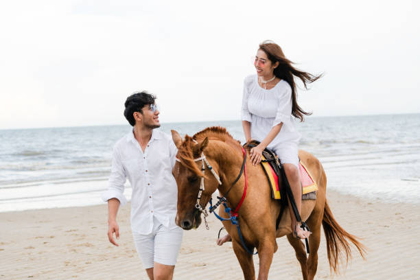 istock Young couple goes horse riding on tropical beach. 1092510556