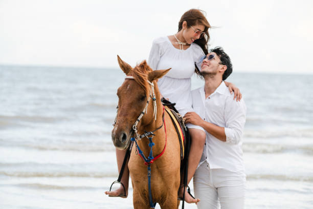 istock Young couple goes horse riding on tropical beach. 1092510570