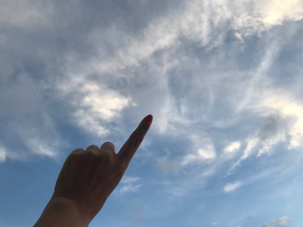 istock woman use her left forefinger pointing up in the bright blue sky with white cloud in daylight 1092516940