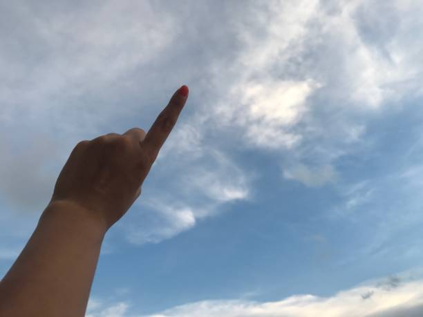 istock woman use her left index finger pointing up in the bright blue sky with white cloud in daylight 1092516944