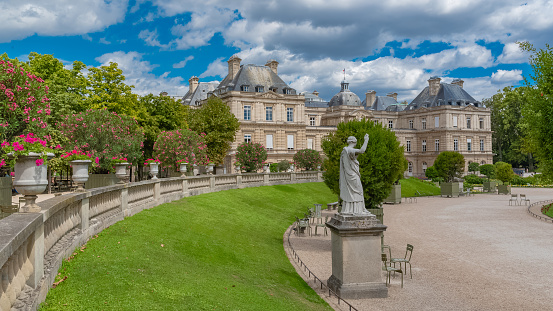 Pedestrians walk in front of Palais du Luxembourg, Luxembourg Palace in Paris, France on a cloudy day.