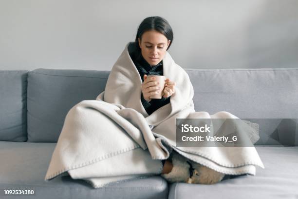 Autumn Winter Portrait Of Young Girl Resting At Home On The Sofa With Cup Of Hot Drink Under Warm Blanket Stock Photo - Download Image Now
