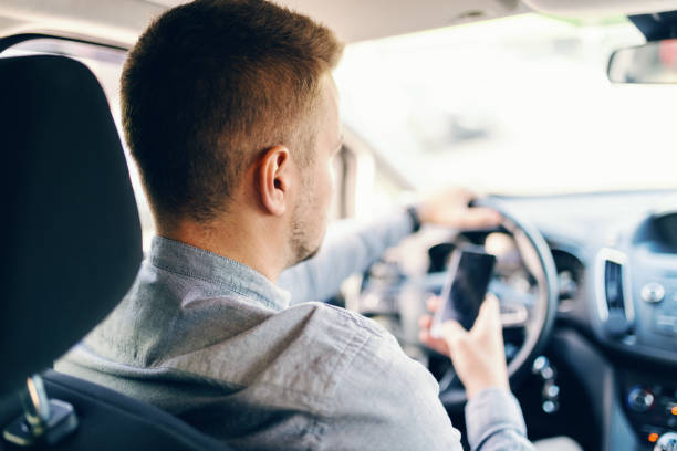 istock Man driving car and using smart phone. Photo taken from backseat. 1092538428