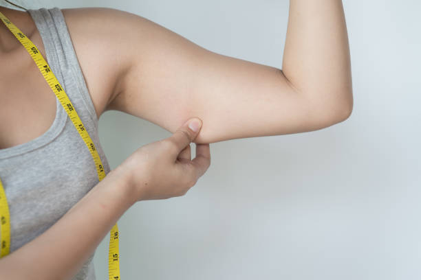 young asian woman feeling worried about her over weight problem and measuring her upper arm size by measuring tape. - upper arm fotos imagens e fotografias de stock