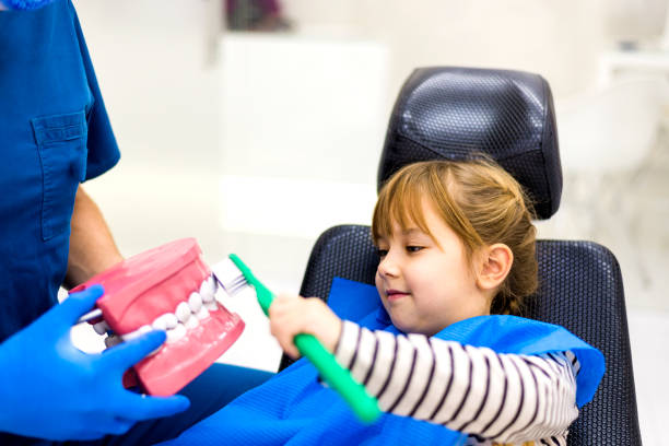 Dentist teaching cute girl about oral hygiene Dentist teaching cute girl about oral hygiene pediatric dentistry stock pictures, royalty-free photos & images