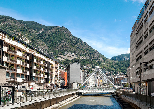 ANDORRA LA VELLA, ANDORRA - SEPTEMBER 2014. Anonymous people walking through the central streets of Andorra on a sunny day. It is a city surrounded by the mountains of the Pyrenees. You can see the river crossing the city and a modern bridge.