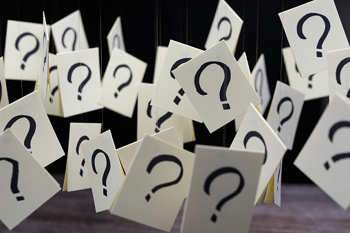 Hanging question mark paper card on wooden table over black