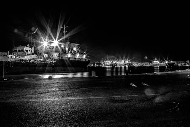 The port of Fos sur Mer by night.\nthe tankers are docked on the docks of the petrochemical plant.\nThe lights form a multitude of stars. Black and white photo