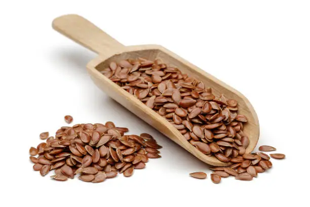 Photo of Flax seeds in wooden spoon on white background