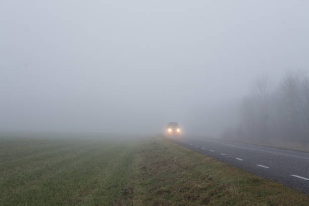 Car driving along a countryside road in heavy fog