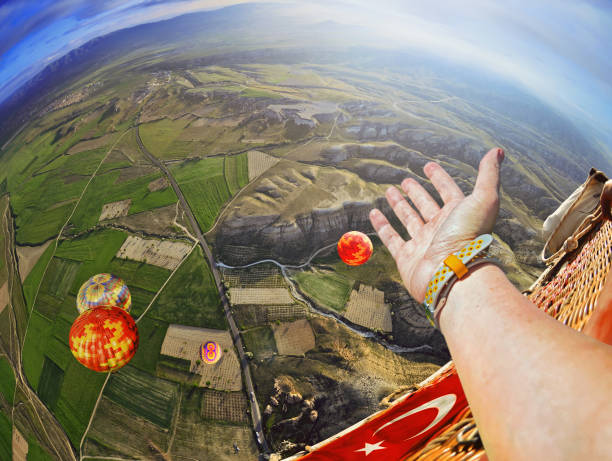 vue d’une main d’une personne dans le ciel. colorful montgolfière survolant paysage rupestre dans un ciel bleu à cappadoce turquie - sun sky child balloon photos et images de collection