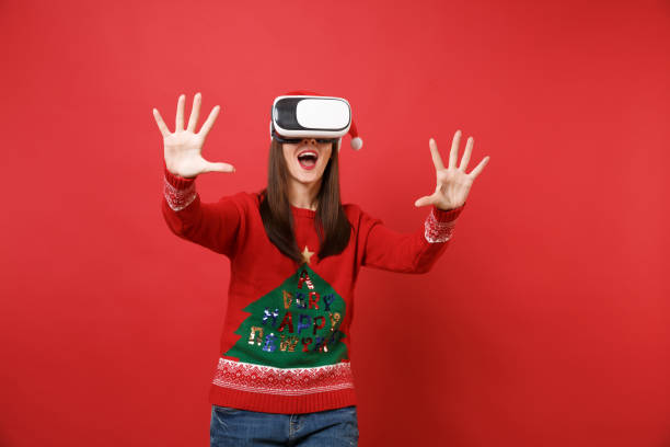 istock Young Santa girl looking in headset touch something like push click on button, pointing at floating virtual screen isolated on red background. Happy New Year 2019 celebration holiday party concept. 1092589610