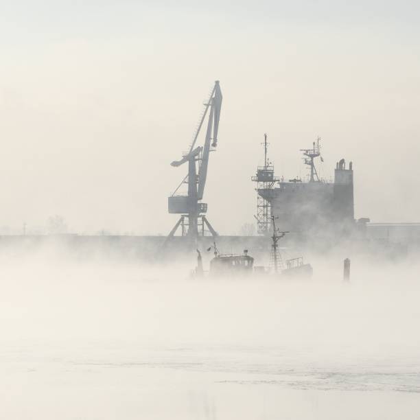 istock Cargo ship and cranes silhouettes in fog 1092606200