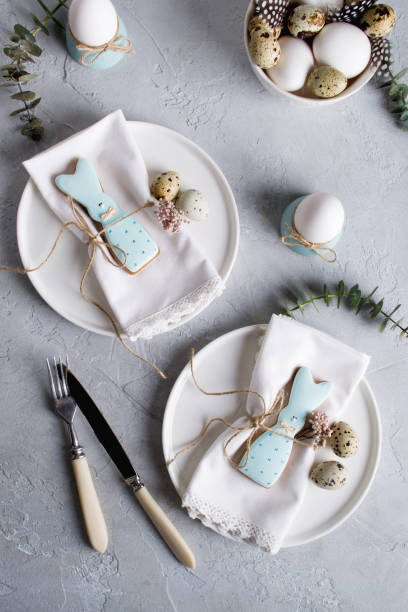 istock Easter  festive table setting with Easter bunny cookies, quail eggs  and chicken egg, green  leaf sprigs of eucalyptus. On a gray concrete background. Holiday celebration decorations. 1092620626