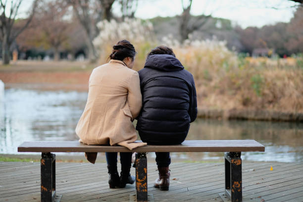 istock Couple sitting on bench and watching smartphone in park 1092621136