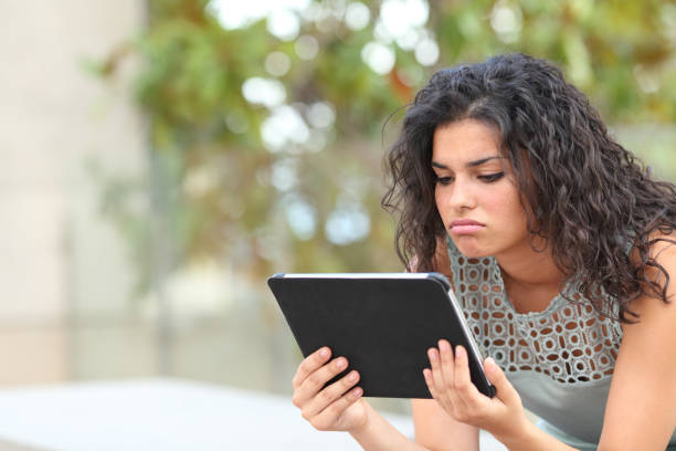 istock Bored woman watching media in a tablet in a park 1092626196