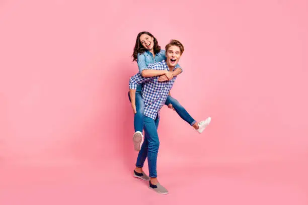 Close up full length body size photo of piggy back hugging she her he him his lady guy boy going to competitions best team wearing casual jeans denim plaid shirts isolated on rose background