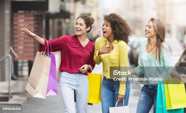 Happy Women With Shopping Bags Walking Along City Street Stock Photo - Download Image Now