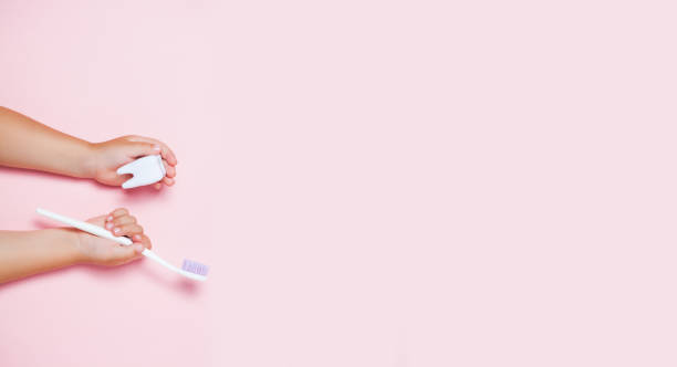 Child's hands holding big tooth and toothbrush