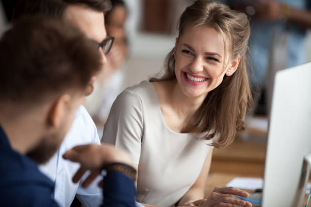 souriante jeune femme parlant avec des collègues du milieu de travail partagé - success businessman corporate business ecstatic photos et images de collection