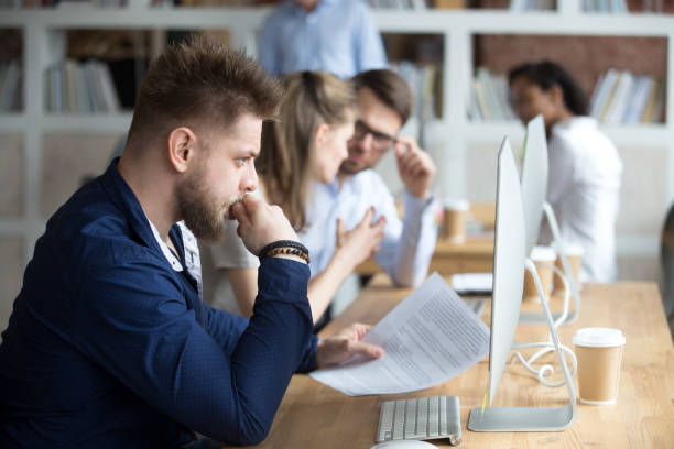 istock Thoughtful employee with paper in hand looking at screen 1092645812