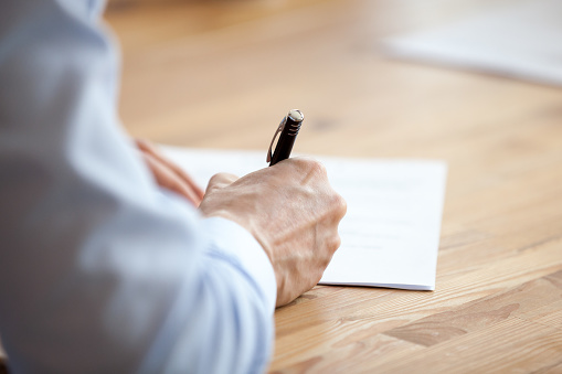 Man hand holding pen, writing notes at meeting close up