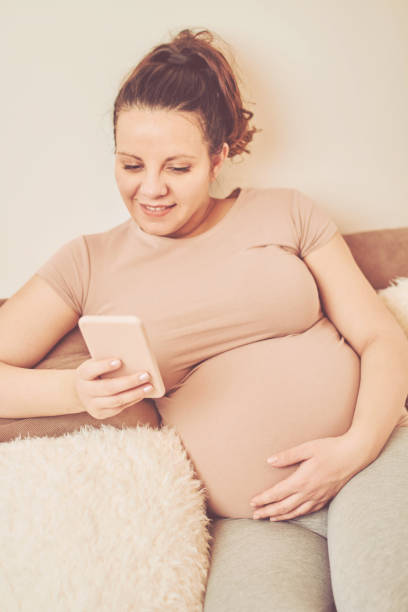 istock Beautiful pregnant woman drinking coffee/tea and using cellphone while enjoying at home. 1092651916