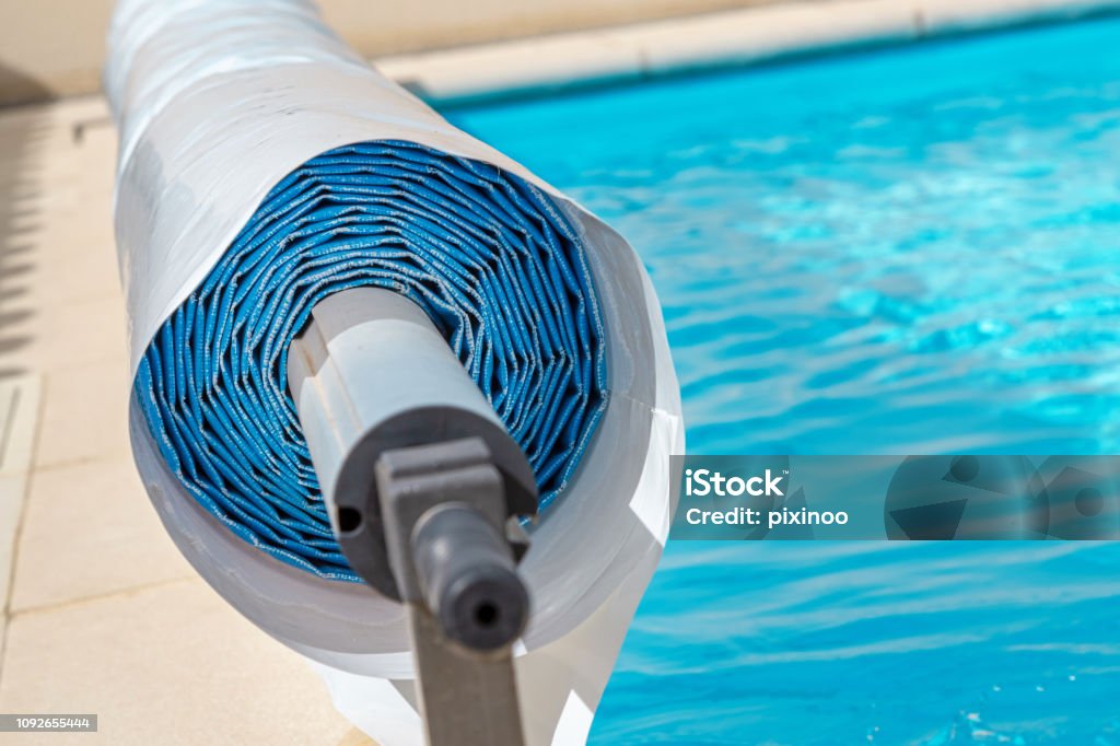 Pool cover on the edge of a pool during the summer closeup on a pool cover on the edge of a pool during the summer Swimming Pool Stock Photo