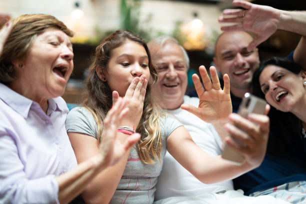 multi-generation hispanic-latino family having a video chat at home - wireless technology cheerful granddaughter grandmother imagens e fotografias de stock