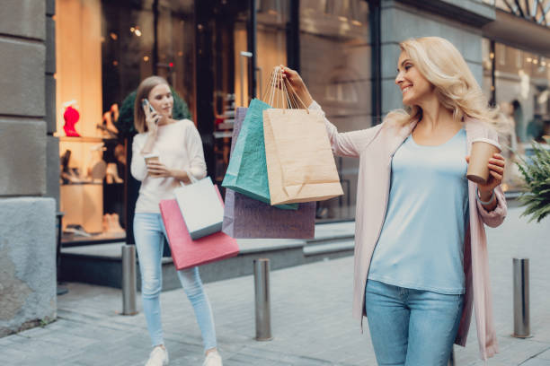 istock Charming lady looking at shopping bags while her daughter talking on cellphone 1092665874