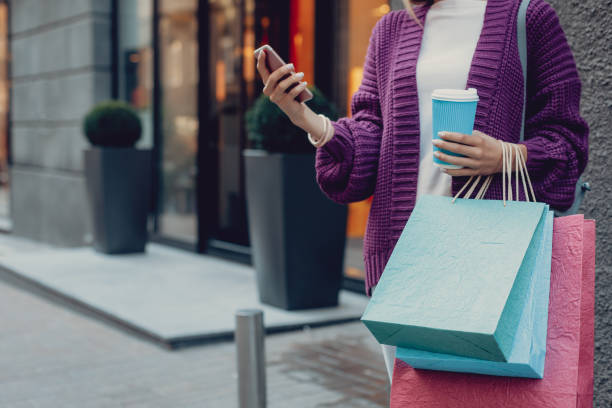 istock Young woman with hot drink using cellphone on the street 1092665932