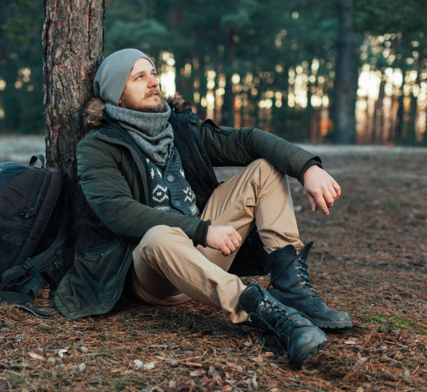 Pensive hipster guy wanderlust with touristic backpack enjoy tranquility during exploring nature environment, male hiker thinking about route to discover