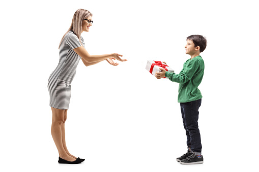Full length shot of a young boy giving a present to his mother isolated on white background