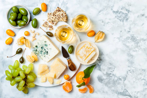 istock Cheese platter with different cheeses, grapes, nuts, honey. Appetizers table with antipasti snacks. Cheese variety board over white marble background. Top view, flat lay 1092682926