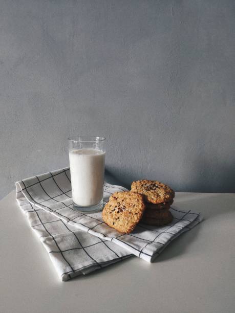 Oatmeal cookies with glass of milk on white towel on grey background. Breakfast time.